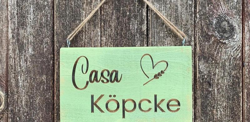 Grünes Holzschild mit dem Schriftzug Casa Köpcke