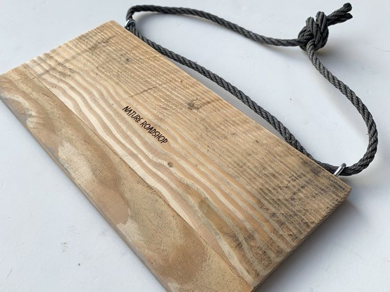 Rückseite eines Holzschilds mit zwei eingedrehten Ösen und verknoteter Kordel