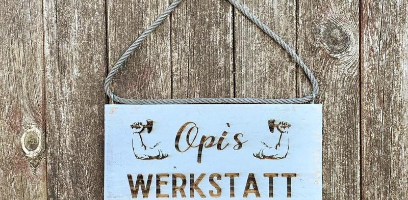 Holzschild an einer Kordel vor einer Bretterwand