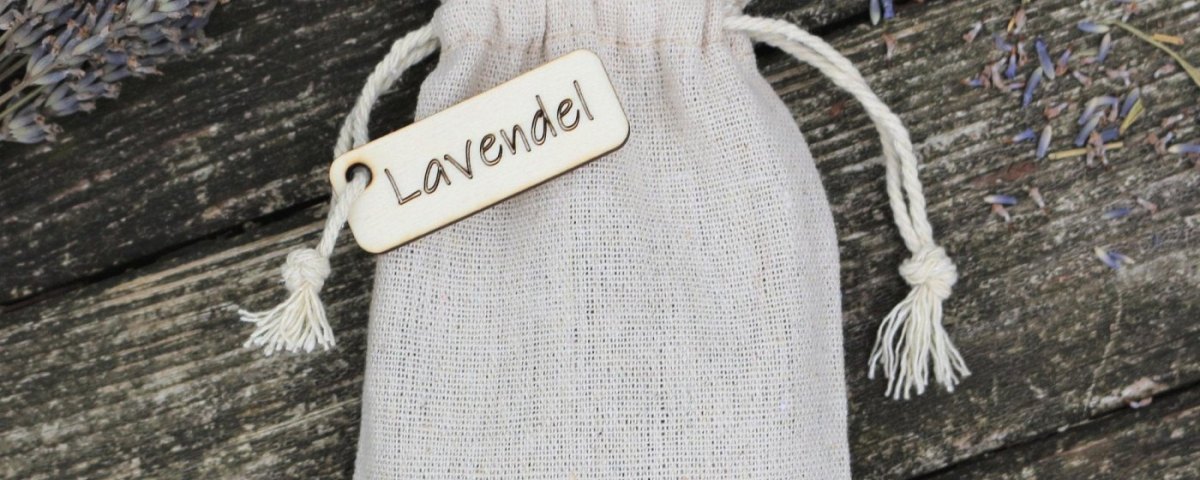 Leinensäckchen mit Holzanhänger und getrocknetem Lavendel auf verwitterten Holzdielen